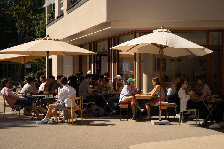 Menschen sitzen unter Sonnenschirmen im Café