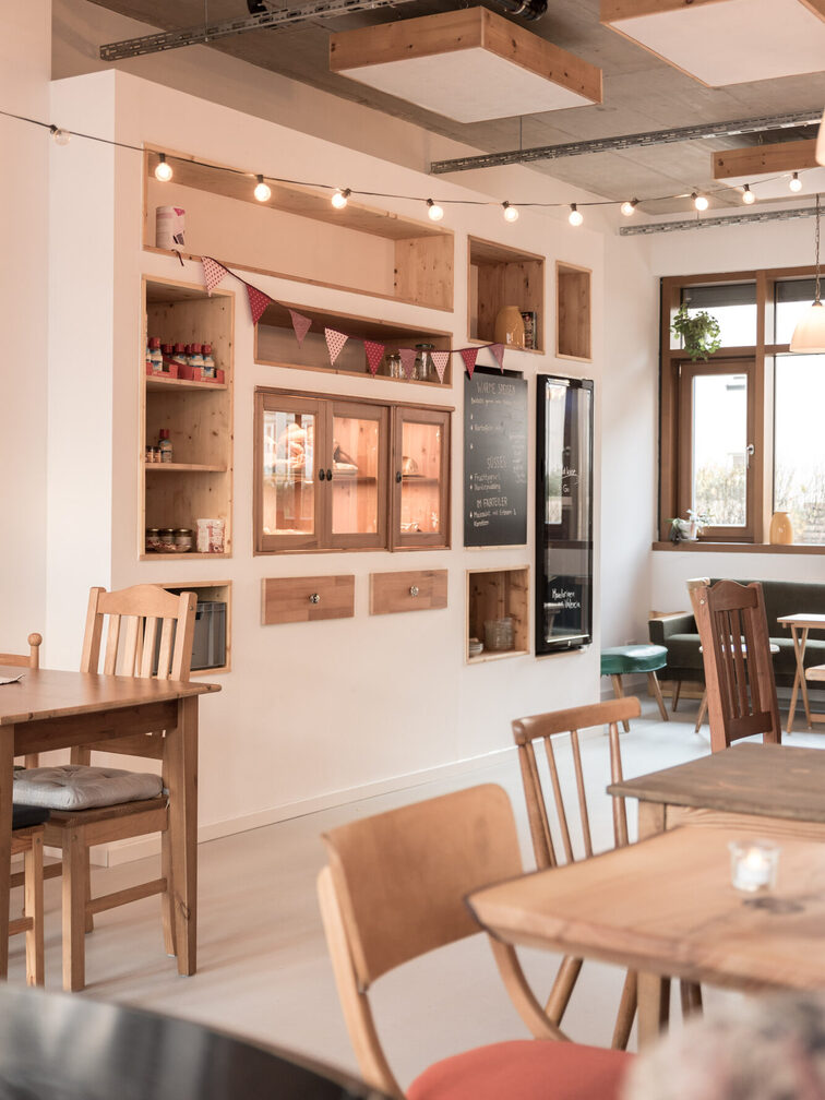 L'intérieur du café Krumm und Schepp avec des meubles rustiques et des guirlandes lumineuses