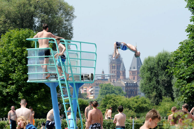 A boy jumping from the three-meter board, the cathedral in the background