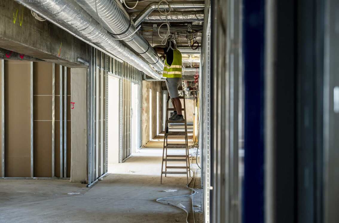 Yıkılan belediye binasında bir işçi merdivenin üzerinde duruyor