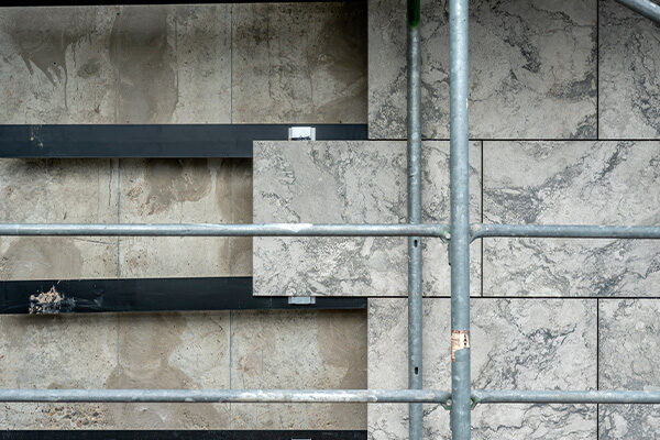 İskeleli belediye binası cephesi: solda dış paneller kaldırılmış, sağda ise hala yerlerinde duruyorlar.