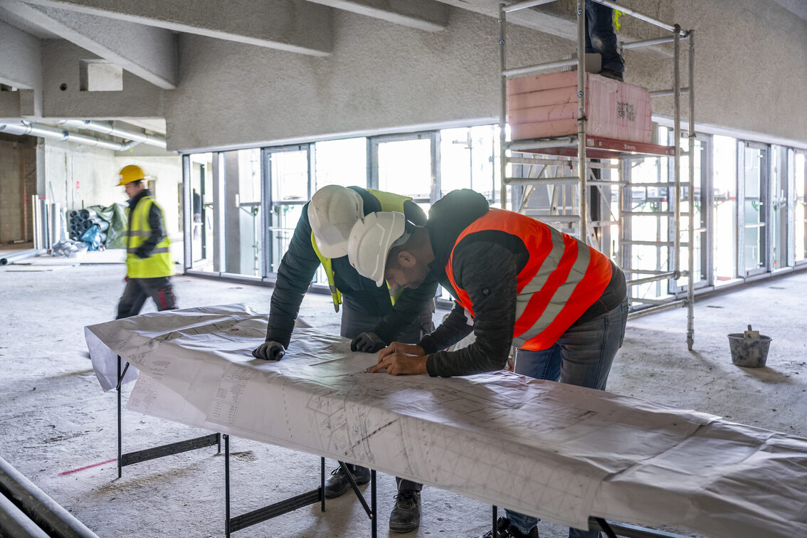 İnşaat alanındaki işçiler plana bakıyor.