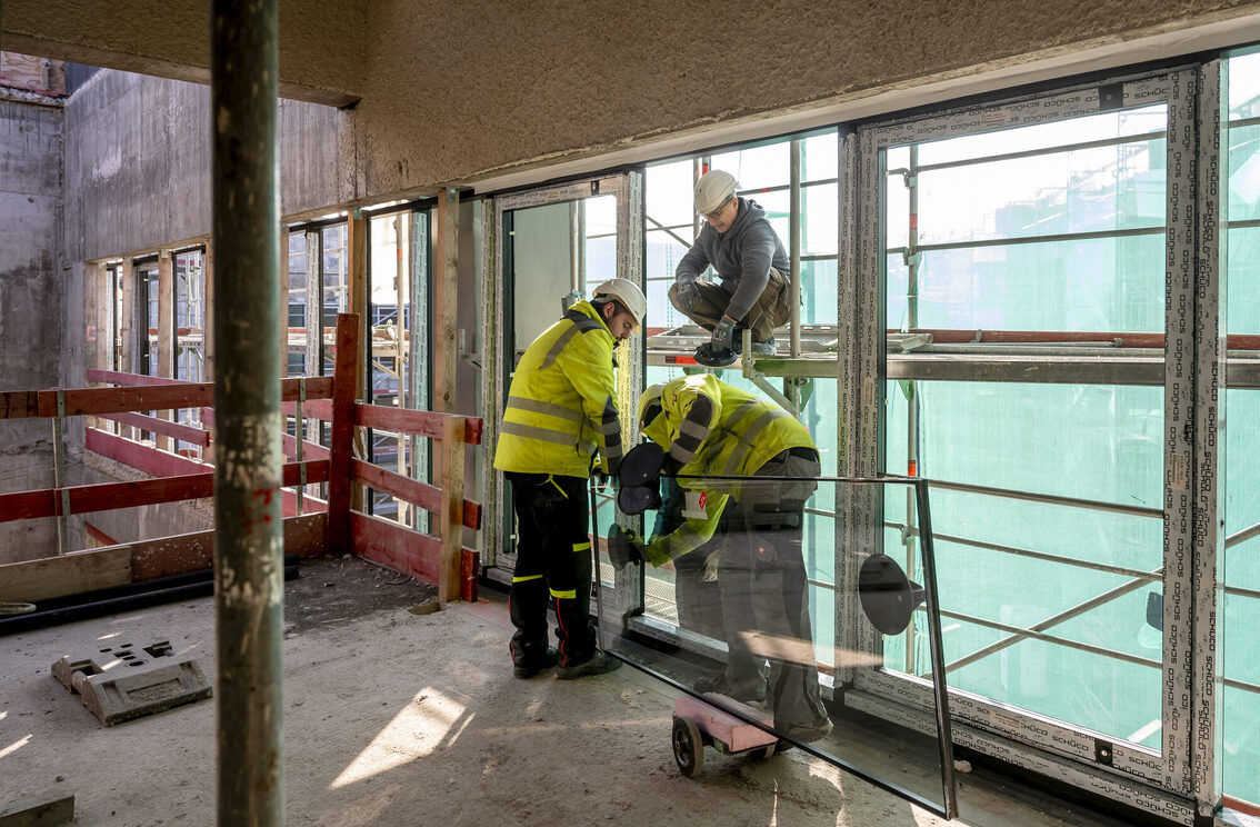 İnşaat işçileri pencereler üzerinde çalışıyor.