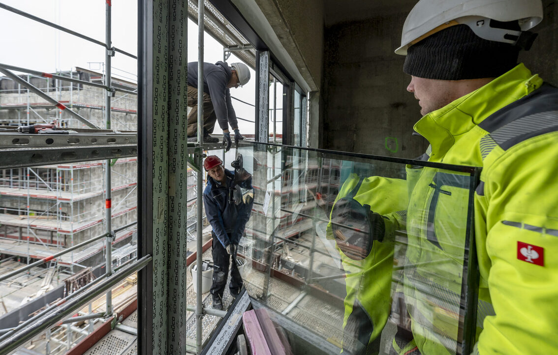 Üç inşaat işçisi bir pencere camı ile birlikte.