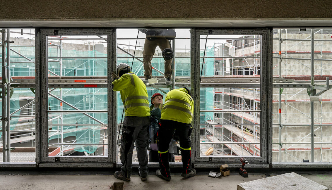 İnşaat işçileri pencere cephesinde çalışıyor.