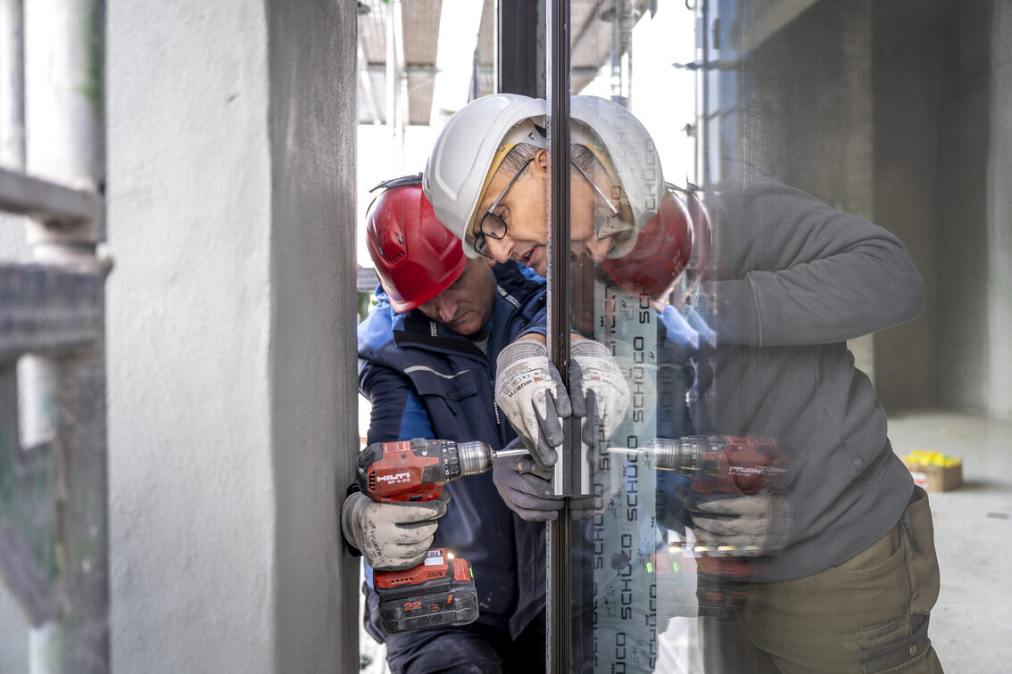 İnşaat işçileri pencere camlarını yerleştiriyor.