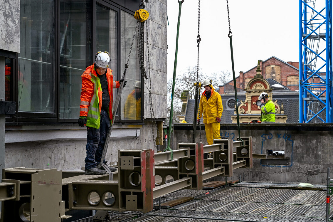 Belediye binası şantiyesindeki inşaat işçileri çelik bir parça yerleştiriyor