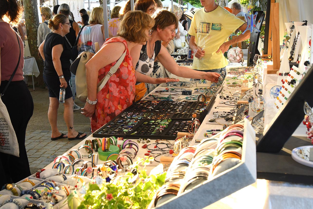 Schmuckstand auf dem Künstlermarkt, Besucherinnen schauen sich den Schmuck an.