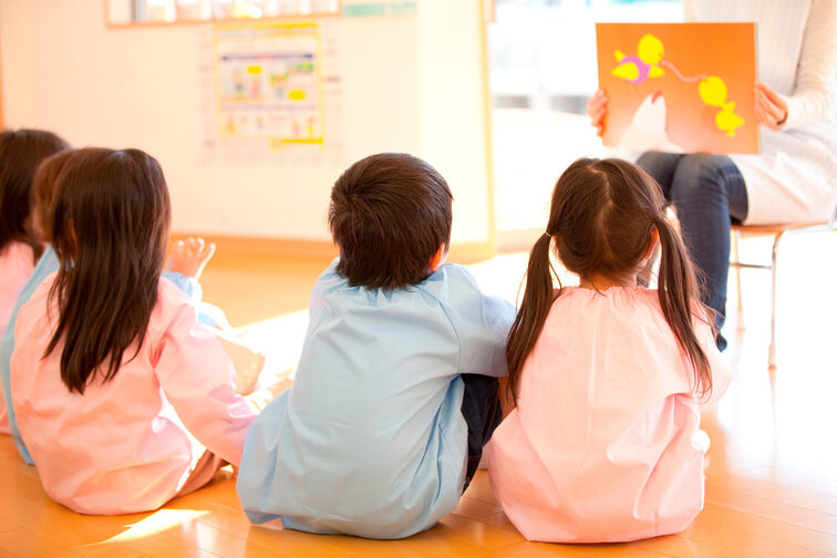 Garde d'enfants, les enfants sont assis devant une animatrice qui montre une image.