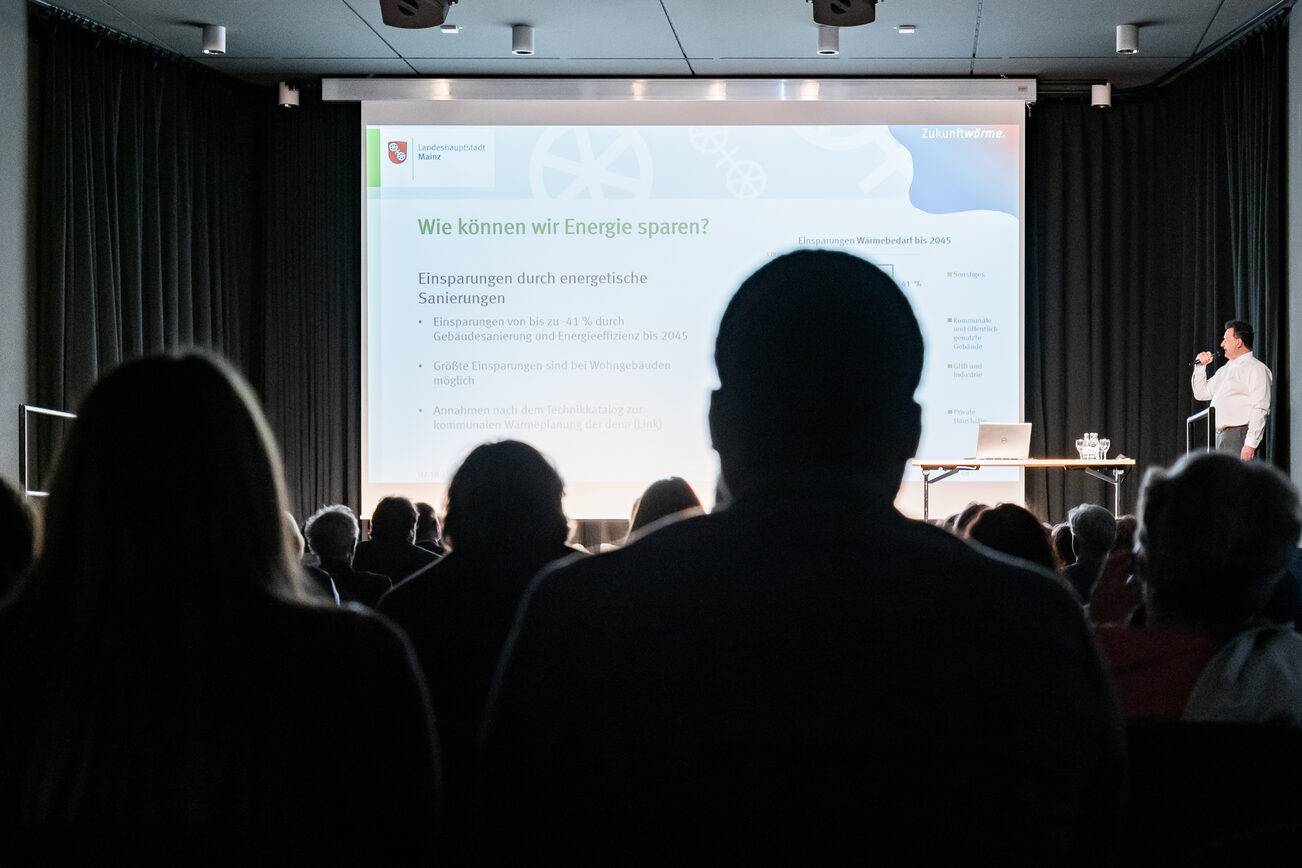 Publikum auf Stühlen lauscht Vortrag