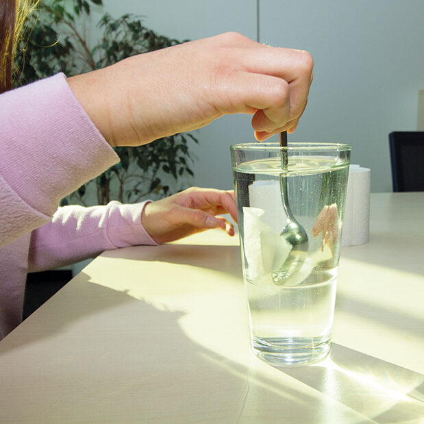 Un morceau de papier toilette est mélangé dans un verre d'eau.