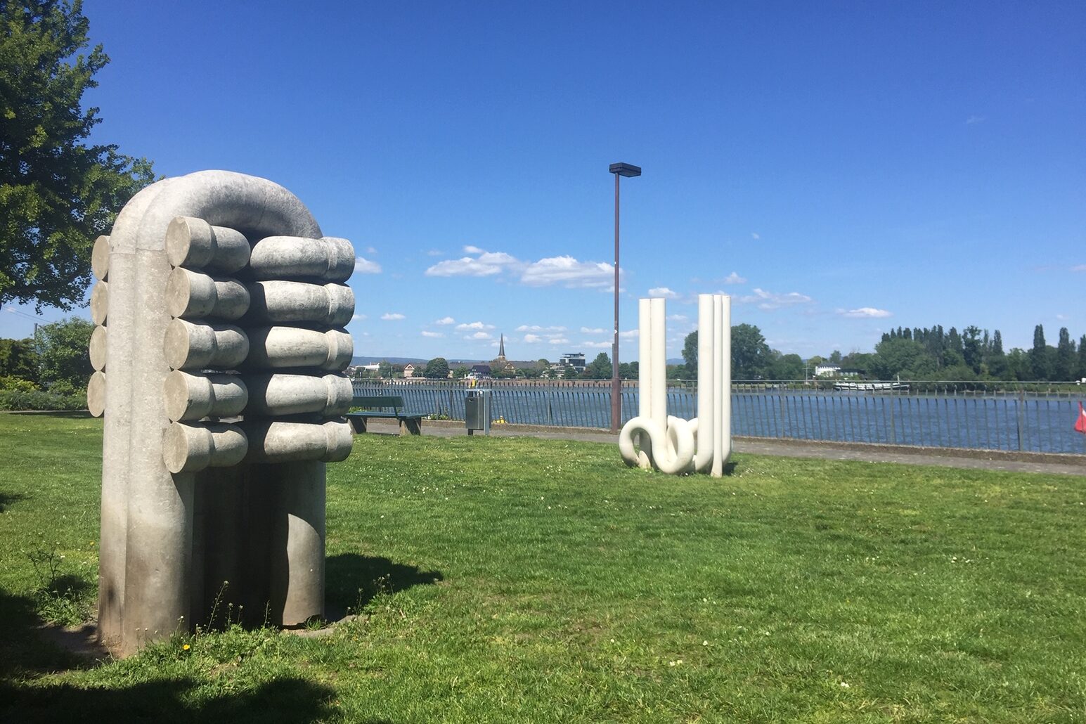 Arka planda Ren Nehri'nin yer aldığı bir çayırda iki sanat eseri.