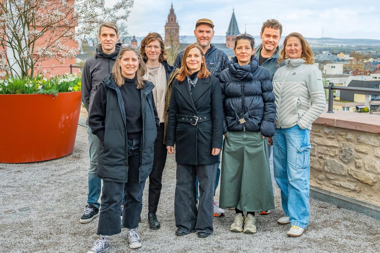 8 people standing outside, flowers and the cathedral in the background.